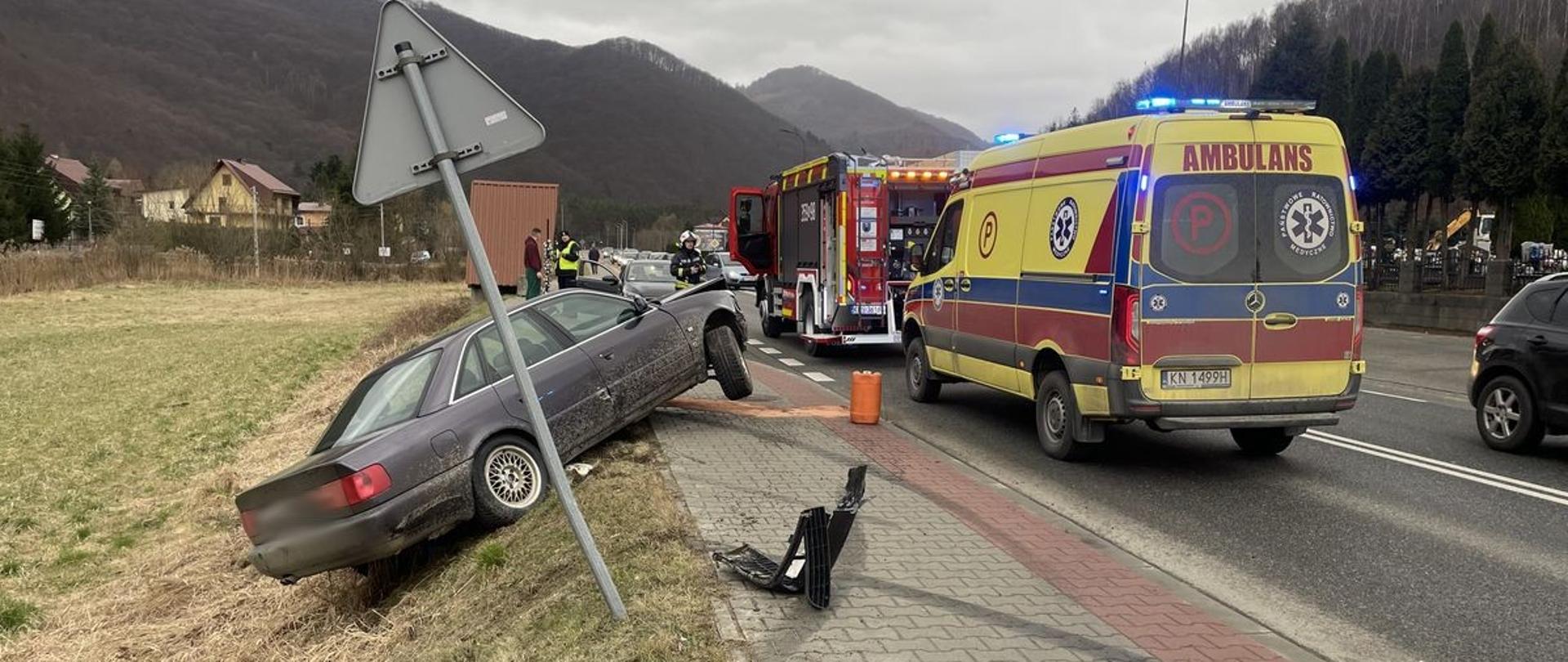 Samochód osobowy na poboczu a na drodze samochody służb ratowniczych