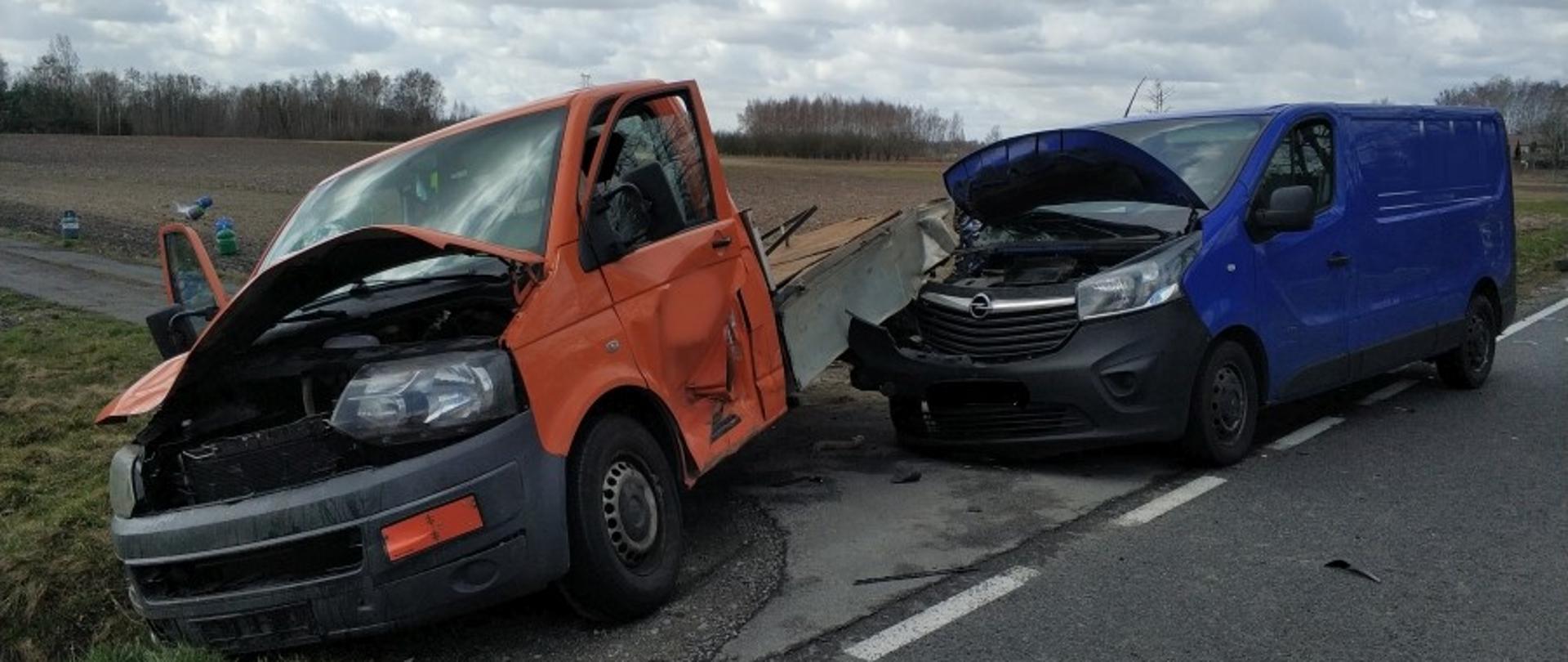 Na zdjęciu widać dwa rozbite samochody dostawcze - pierwszy, pomarańczowy, służący do przewozu butli z gazem, którego tył oparty jest o przód drugiego - granatowego.