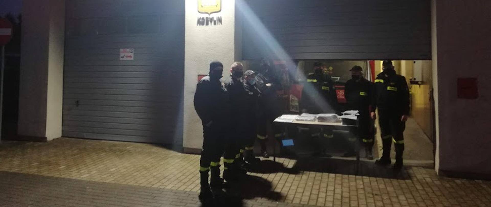 strażacy czekający przed garażem remozy aby odebrać ulotki