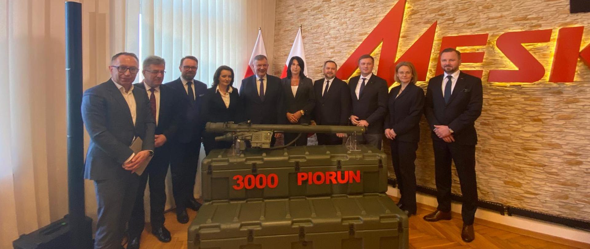 Przedstawiciele strony rządowej i spółek stoją na tle napisu MESKO. Przed nimi 3000 PPZR Piorun. 