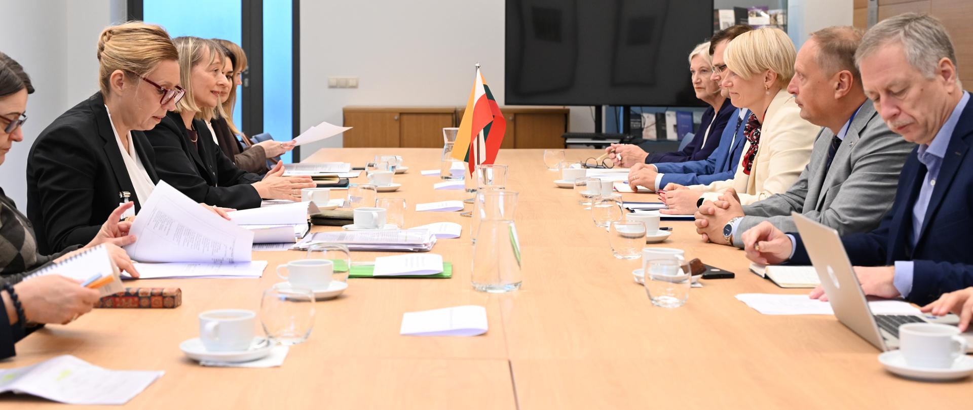 Two groups of officials are sitting at the conference table, facing each other 
