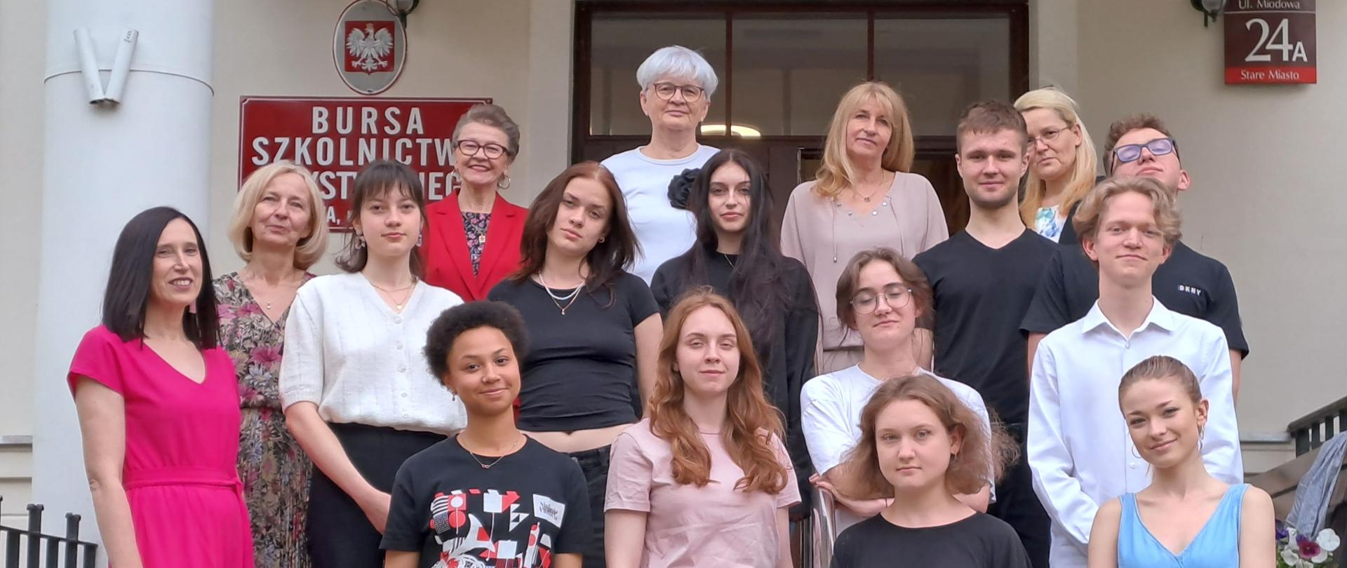 Na schodach, przed wejściem do bursy do wspólnego zdjęcia pozują maturzyści, dyplomanci, pani Dyrektor oraz wychowawcy. 
