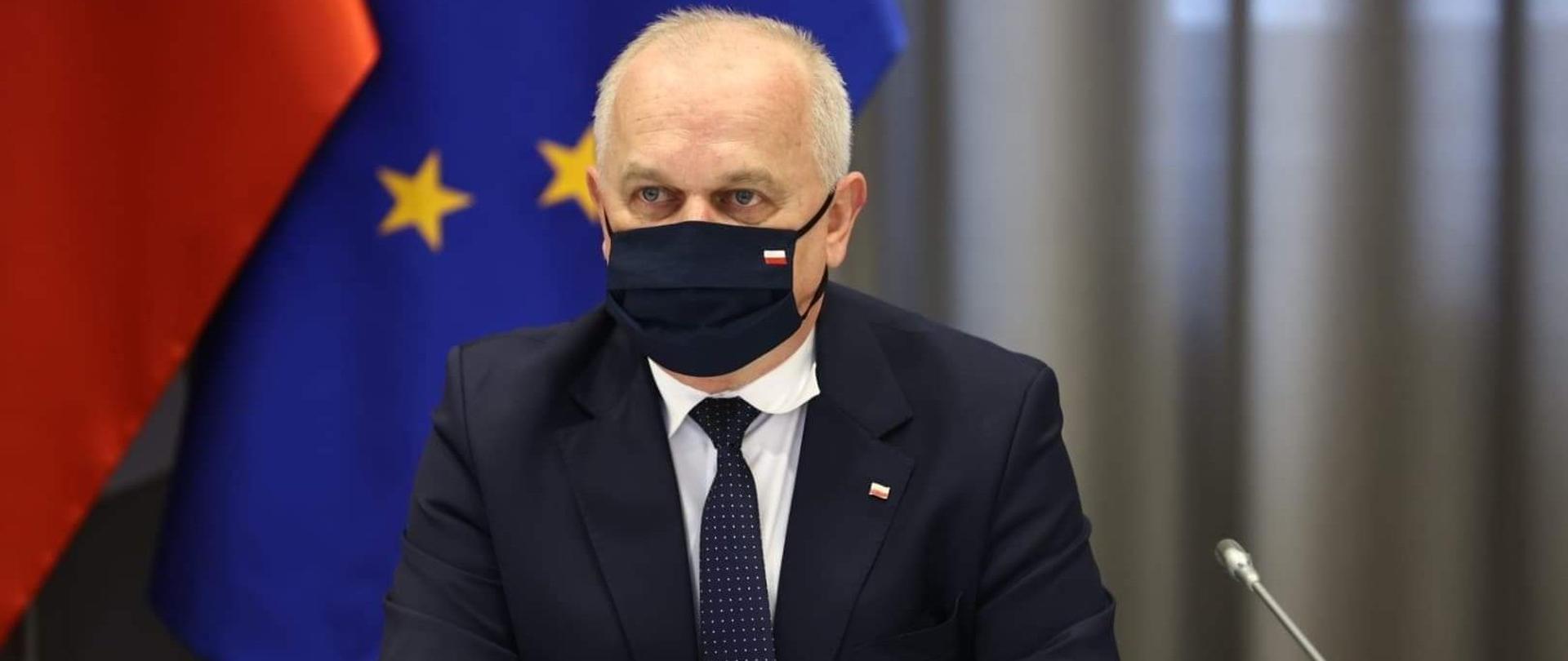 Wojewoda Lubuski w czasie wideokonferencji w siedzibie MSWiA. W tle flagi