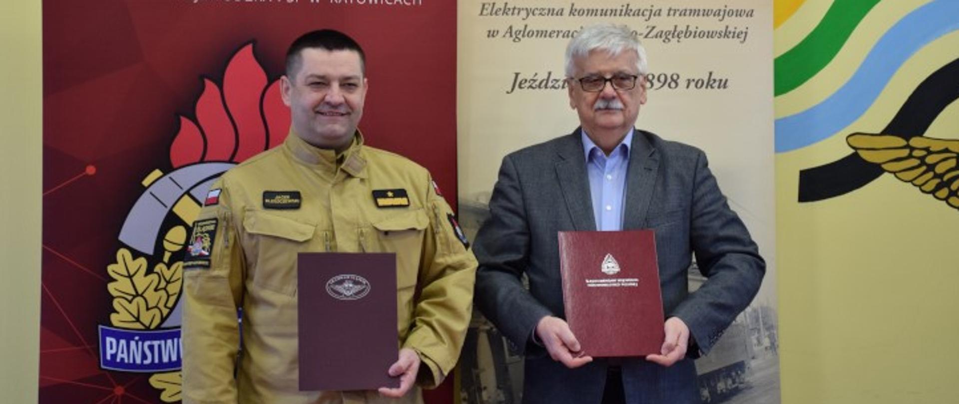 Śląski Komendant Wojewódzki PSP nadbryg. Jacek Kleszczewski oraz Prezes Zarządu Tramwajów Śląskich S.A. Bolesław Knapik prezentują porozumienie, w tle baner Państwowej Straży Pożarnej oraz Tramwajów Śląskich S.A. 