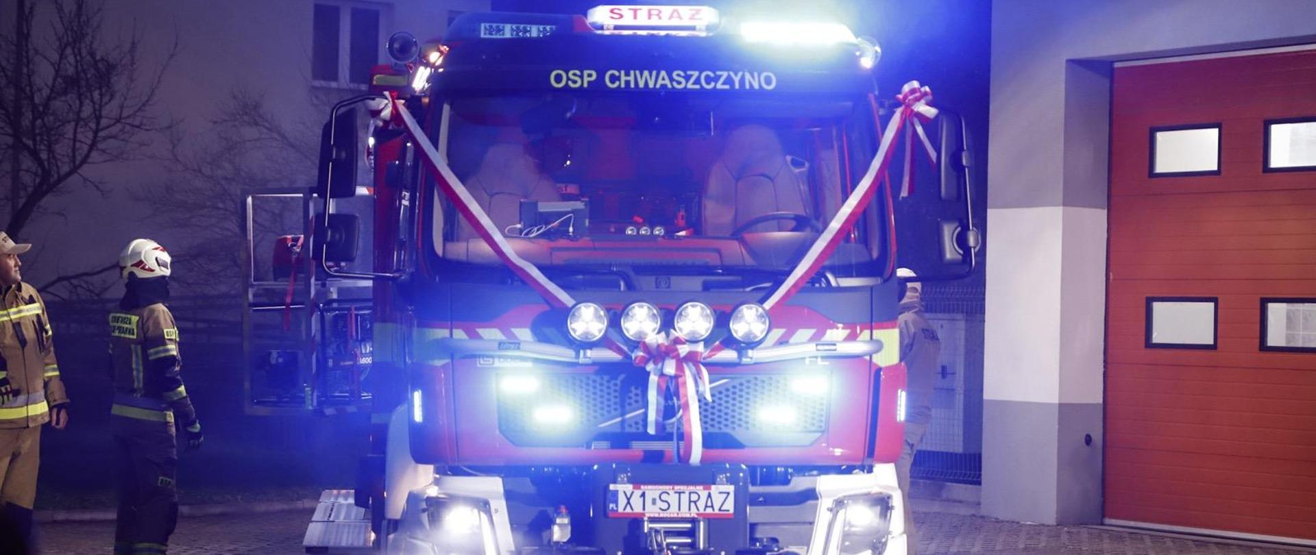 Na zdjęciu widoczny jest nowy samochód OSP Chwaszczyno zaparkowany przed budynkiem remizy