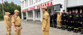 Na zdjęciu widać strażaków ustawionych w dwu szeregu przed wjazdem do garażu strażnicy. Przed strażakami stoi Kierownictwo KM PSP w Gdańsku. Komendant Miejski PSP w Gdańsku przyjmuje meldunek od Dowódcy Jednostki Ratowniczo-Gaśniczej nr 6. W tle na budynku widać duży napis: "PAŃSTWOWA STRAŻ POŻARNA" widoczny jest też maszt na którym powiewa flaga Polski.