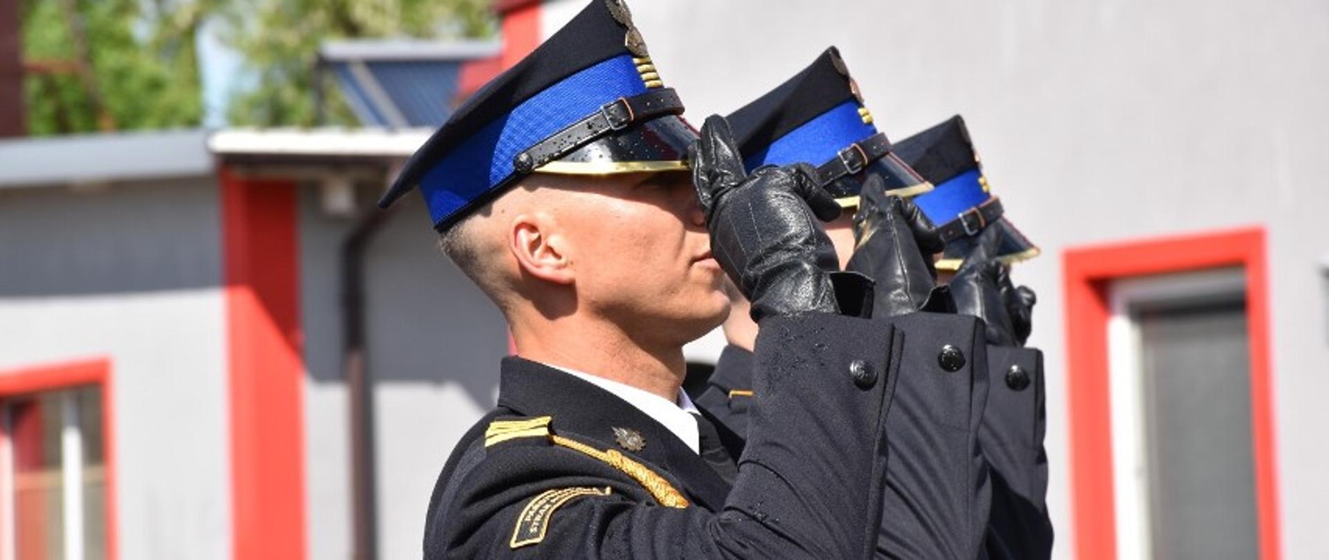 Strażacy salutują do hymnu.