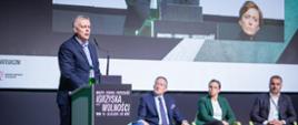 Minister Tomasz Siemoniak stoi przy mównicy. W tle paneliści uczestniczący w dyskusji "Odporne państwo"