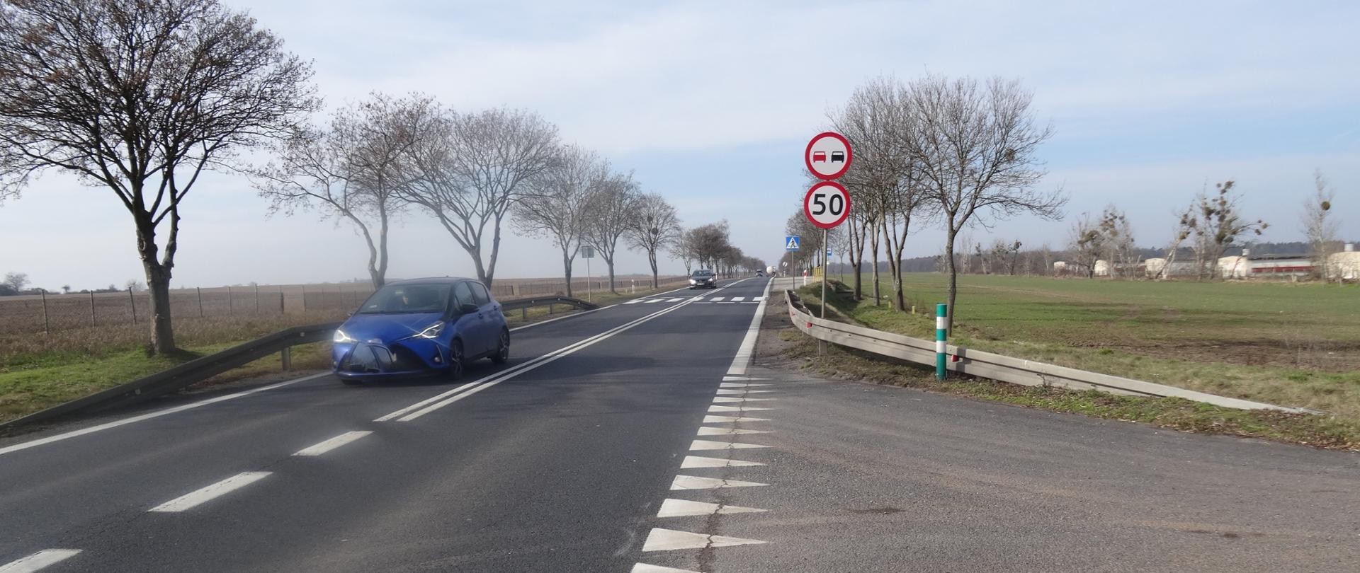 na zdjęciu widoczna droga jednojezdniowa, na drodze pojazdy, w tle przejście dla pieszych