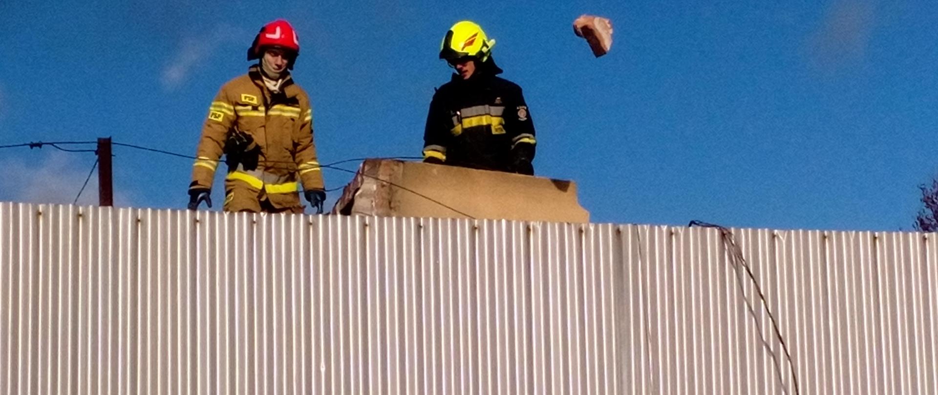Na zdjęciu strażacy usuwają z dachu elementy przewróconego komina