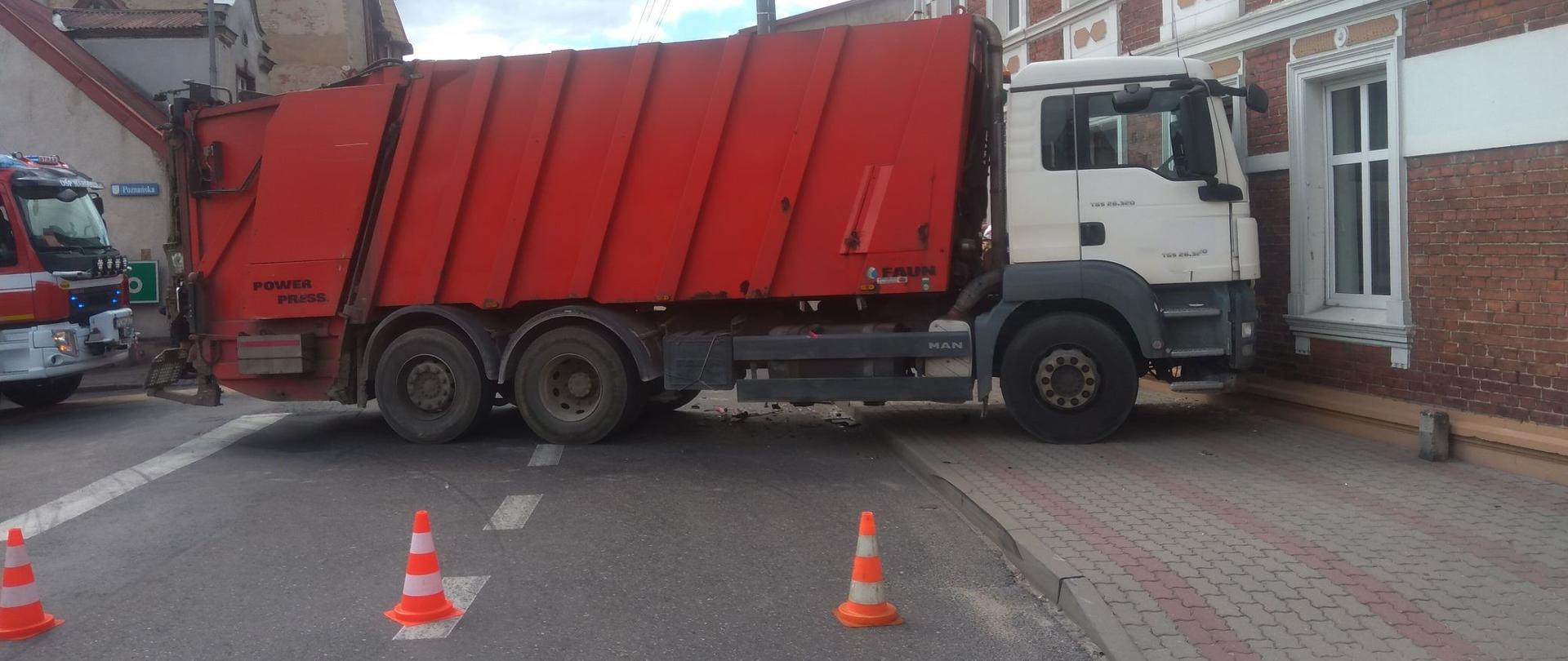 Zdjęcie przedstawia strażaków usuwających skutki kolizji drogowej oraz uszkodzone pojazdy.
W tle budynki wielorodzinne.
