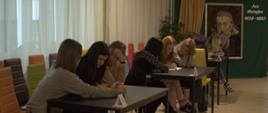 Uczestniczki w grupach trzyosobowych siedzą przy stolikach. W głębi ekran z portretem Matejki i jego nazwiskiem. 