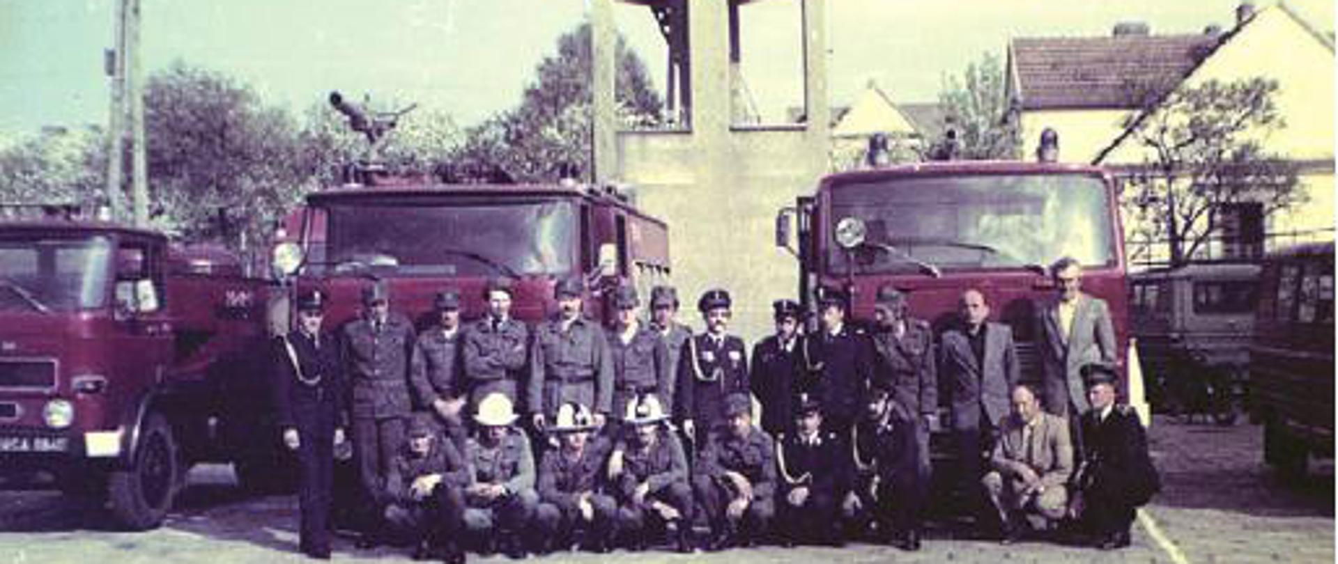  Dzień Strażaka, druga połowa lat 70 XX w. Dzień Strażaka lata 90 XX w. Strażacy w umundurowaniach podczas uroczystego apelu przed wspinalnią starej komendy Zawodowej Straży Pożarnej w Limanowej na tle pojazdów pożarniczych. 