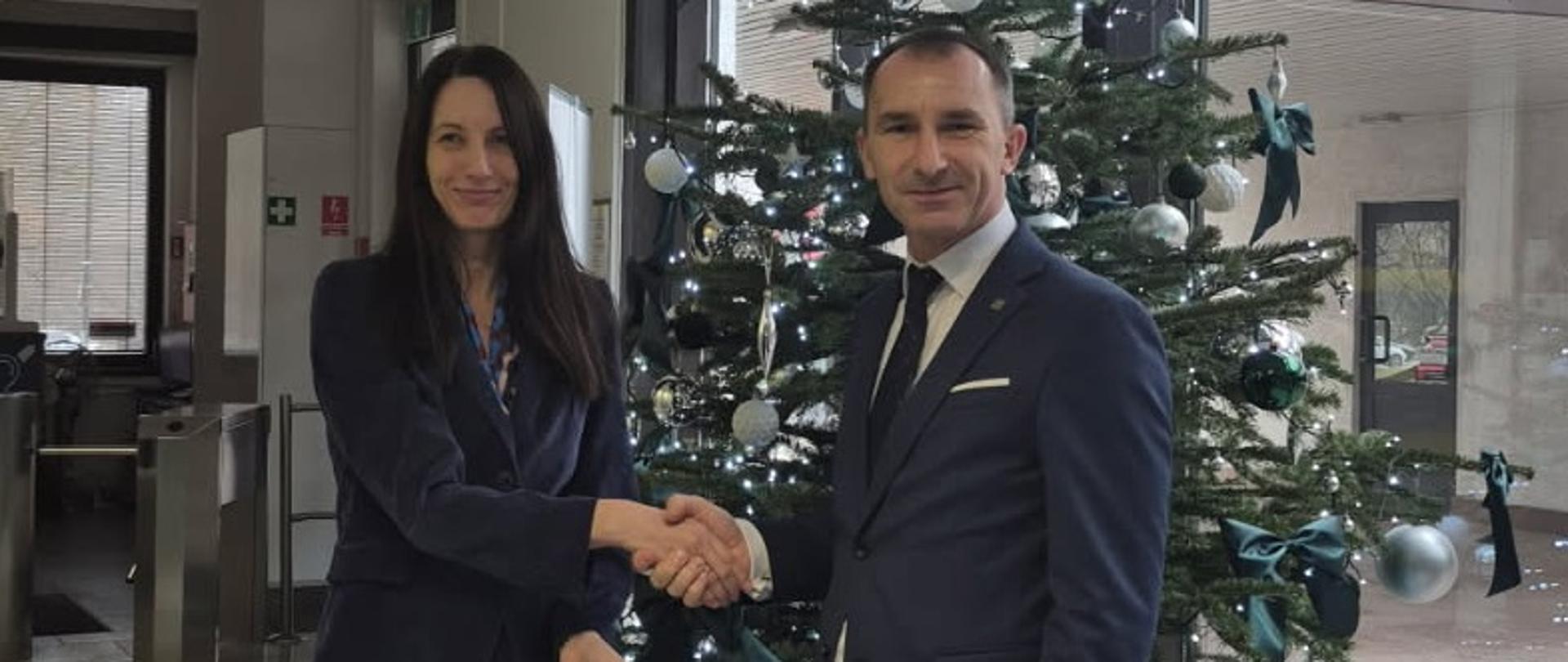 Dwie osoby podające sobie dłonie pod choinką