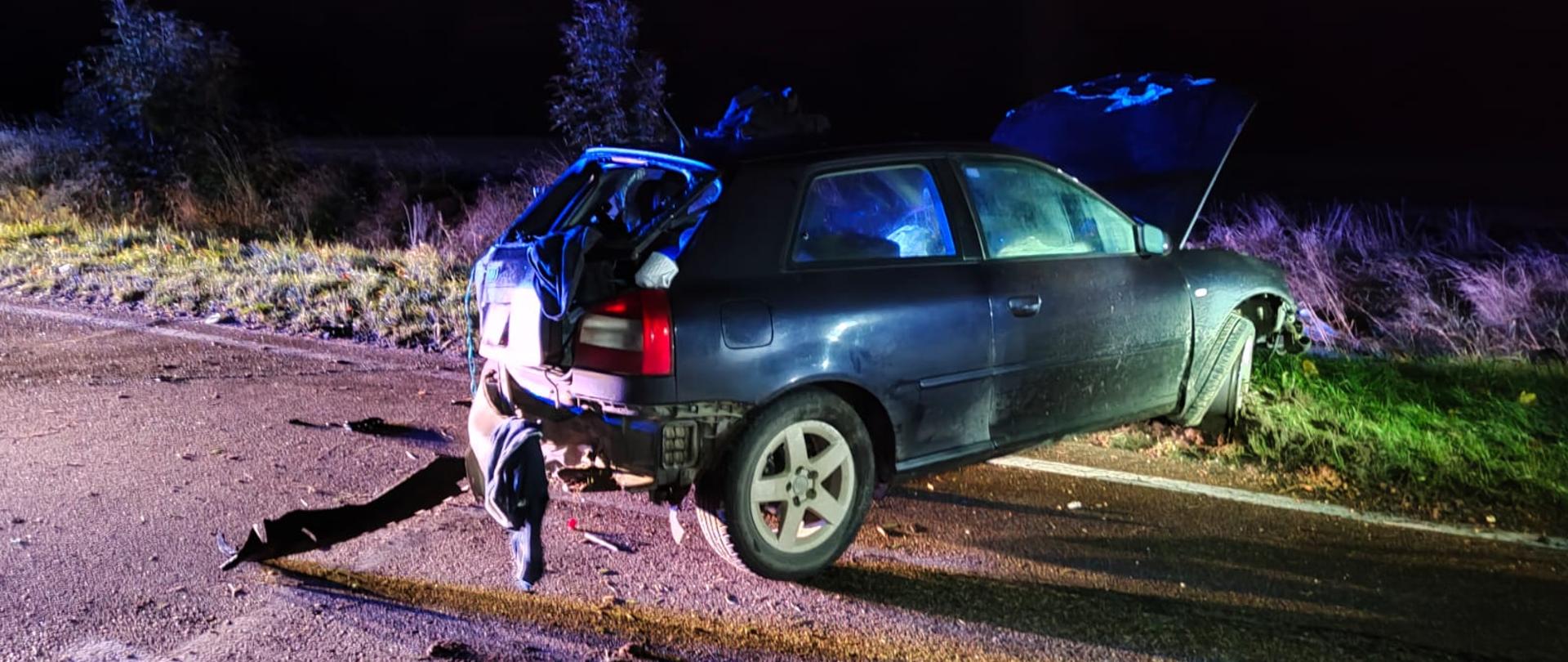 Zdjęcie przedstawia rozbity tył samochodu osobowego stający częściowo na drodze