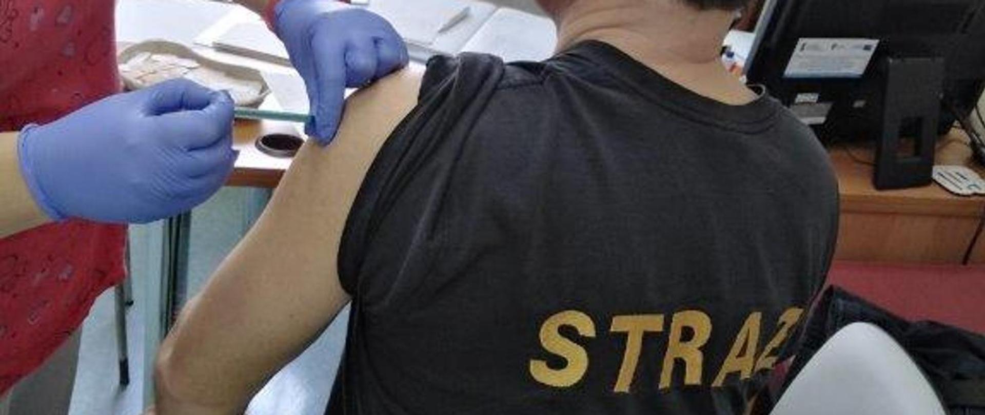 Strażak otrzymujący dawkę szczepionki przeciw COVID-19