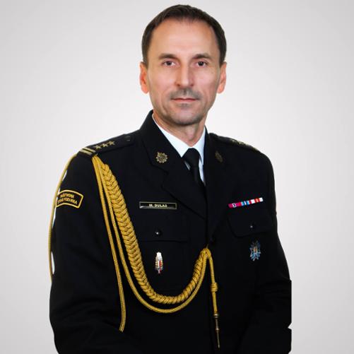 zdjęcie przedstawia starszego brygadiera Marcina Dulasa Łódzkiego Komendanta Wojewódzkiego PSP w mundurze wyjściowym. Zdjęcie portretowe