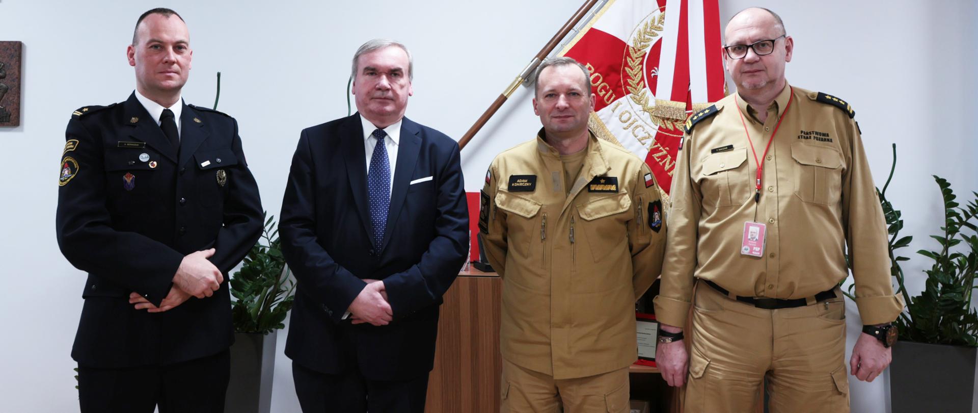 Na zdjęciu znajduje się strażacy pozujący do zdjęcia na tle sztandaru 