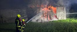 Widać dwóch strażaków podczas gaszenia, wewnątrz jest ogień
