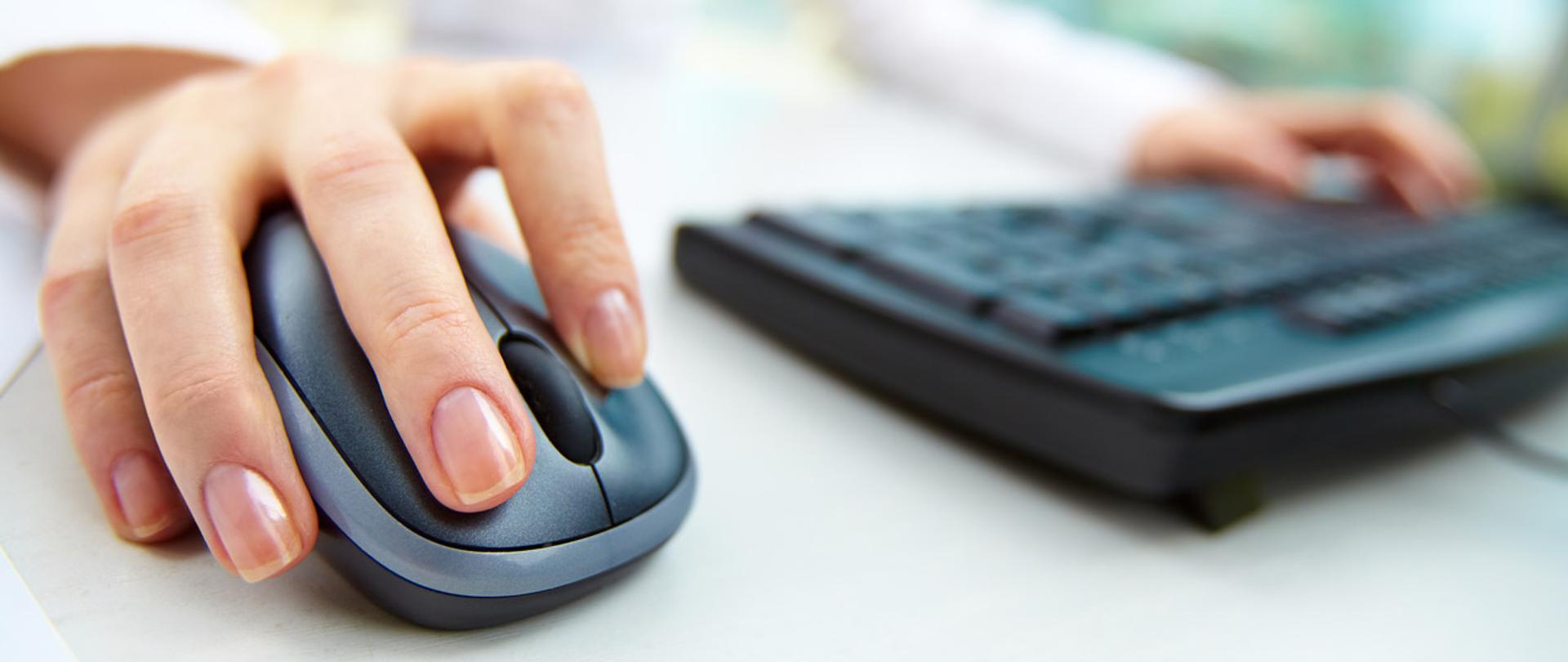 Dłoń na myszce komputerowej i klawiatura komputera.