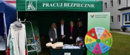 Kobieta, mężczyzna, dwie kobiety stojące pod namiotem stoiska informacyjnego