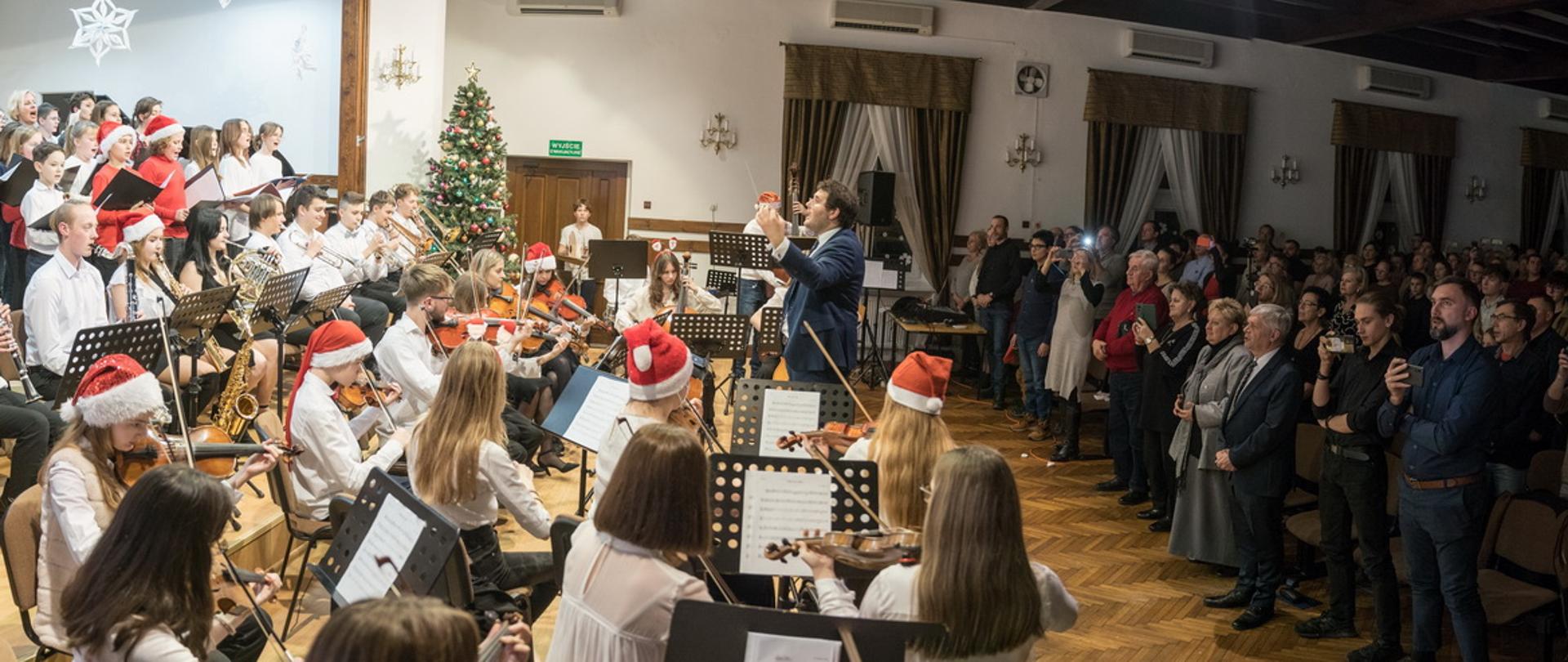 Zdjecie przedstawia orkiestrę szkolną i chór pod batutą Jakuba Unolta..