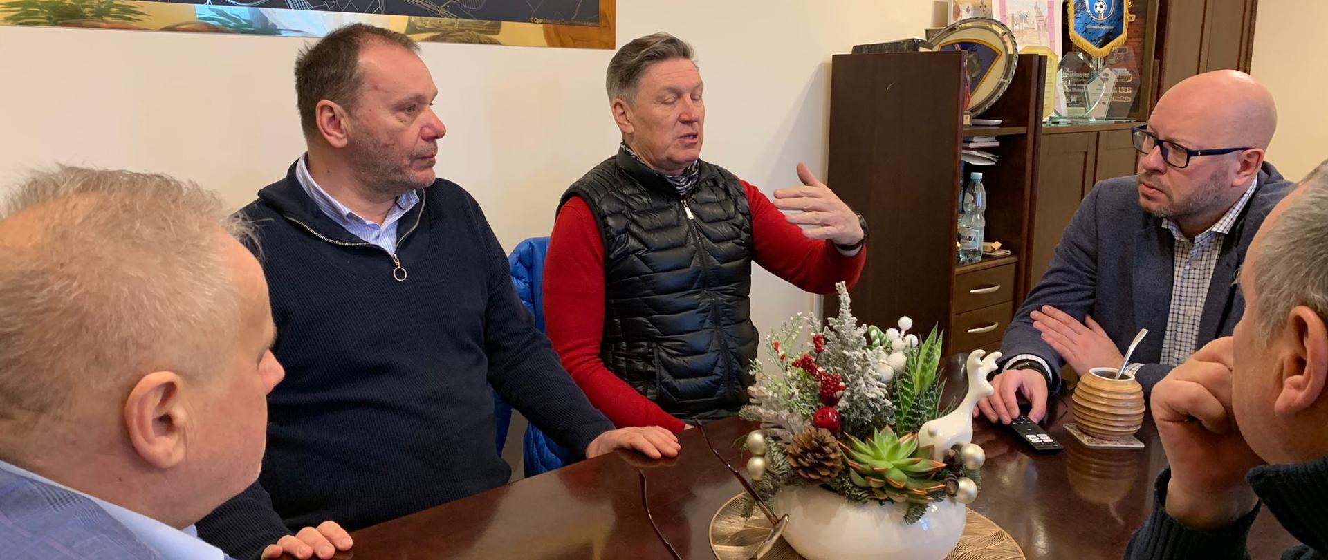 Pięciu mężczyzn podczas rozmowy przy stole