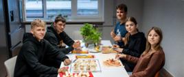 Grupa uczniów przy stole przygotowuje posiłek