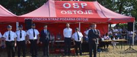 Zawody sportowo-pożarnicze w Jeziorach. Plac ćwiczeń. Na tle namiotów i członków komisji sędziowskiej do drużyn, które wystartowały w zawodach przemawia burmistrz miasta i gminy. 