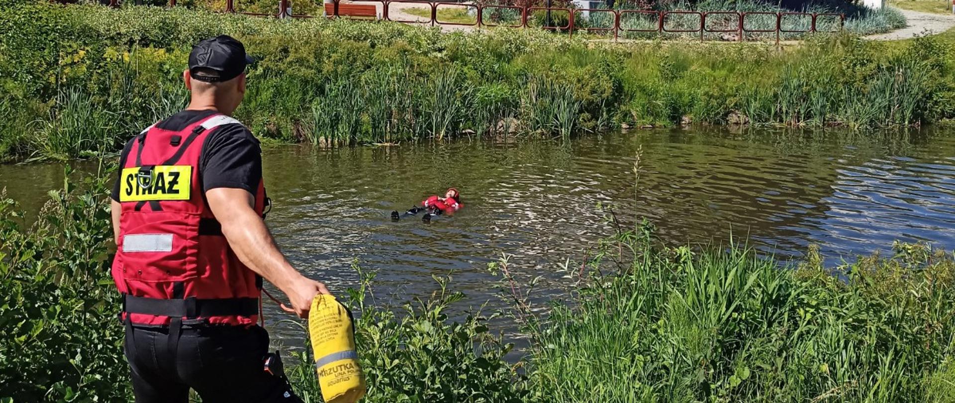 ratownik PSP rzucający rzutką do osoby znajdującej się w wodzie