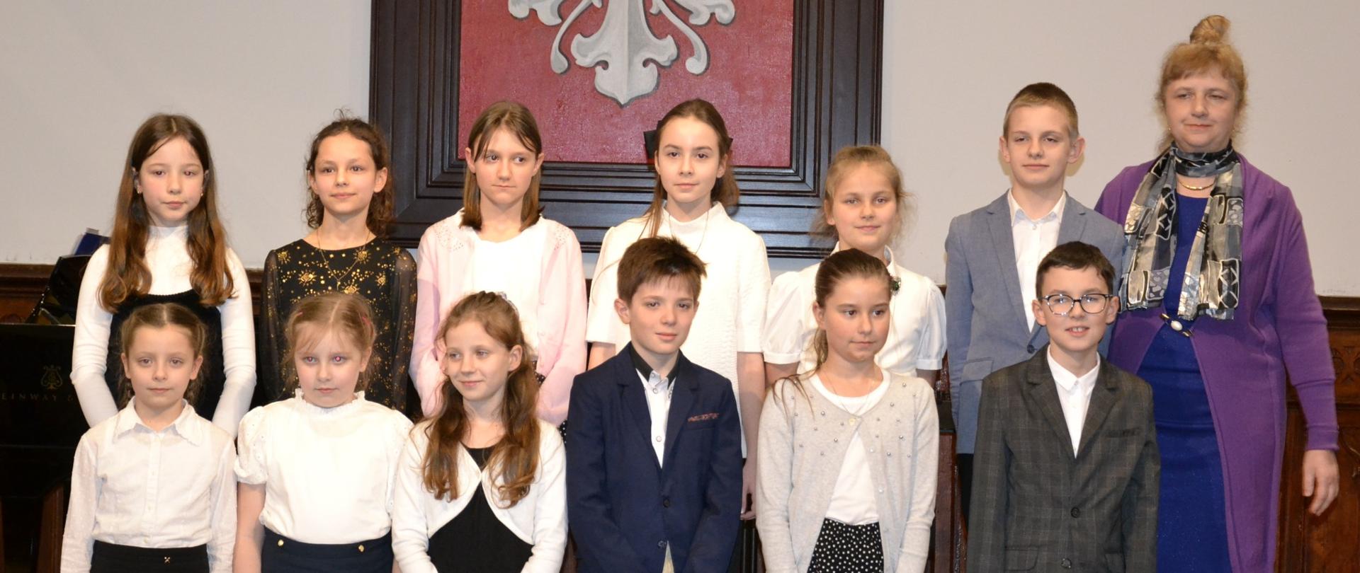 uczniowie klasy III A i B cyklu 6-letniego PSM I stopnia na scenie w Sali Królewskiej podczas koncertu klasowego wraz z nauczycielką Aleksandrą Klupś