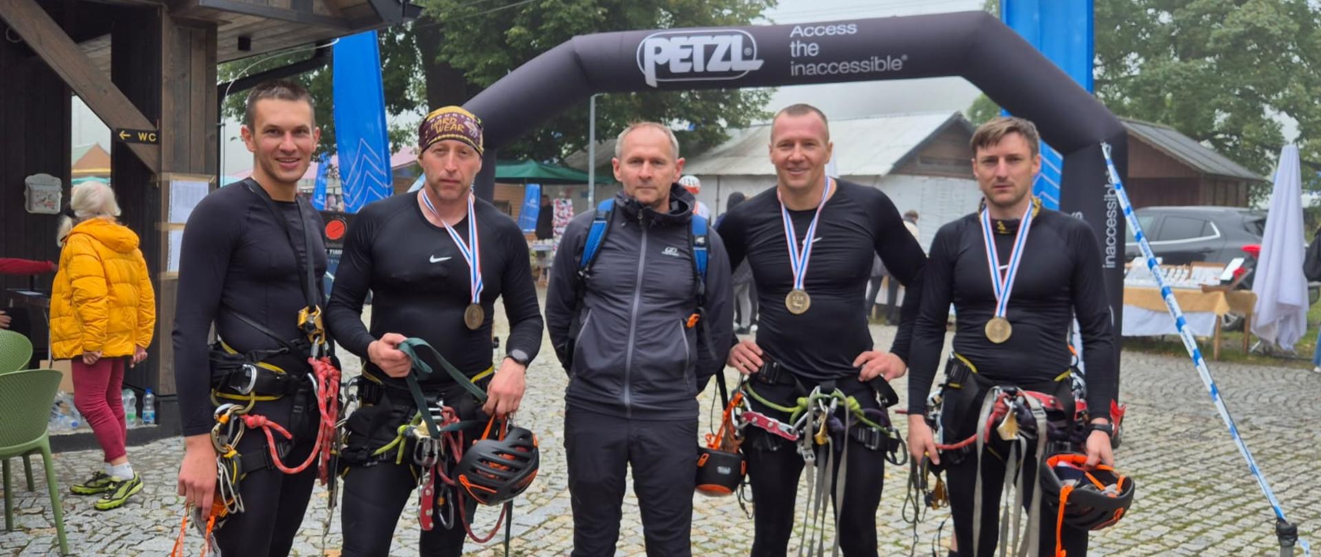 Drużyn KM PSP w Bydgoszczy stojąca w szeregu na placu z kostki. Drużyna pięcioosobowa. Wszyscy w sportowych strojach. 