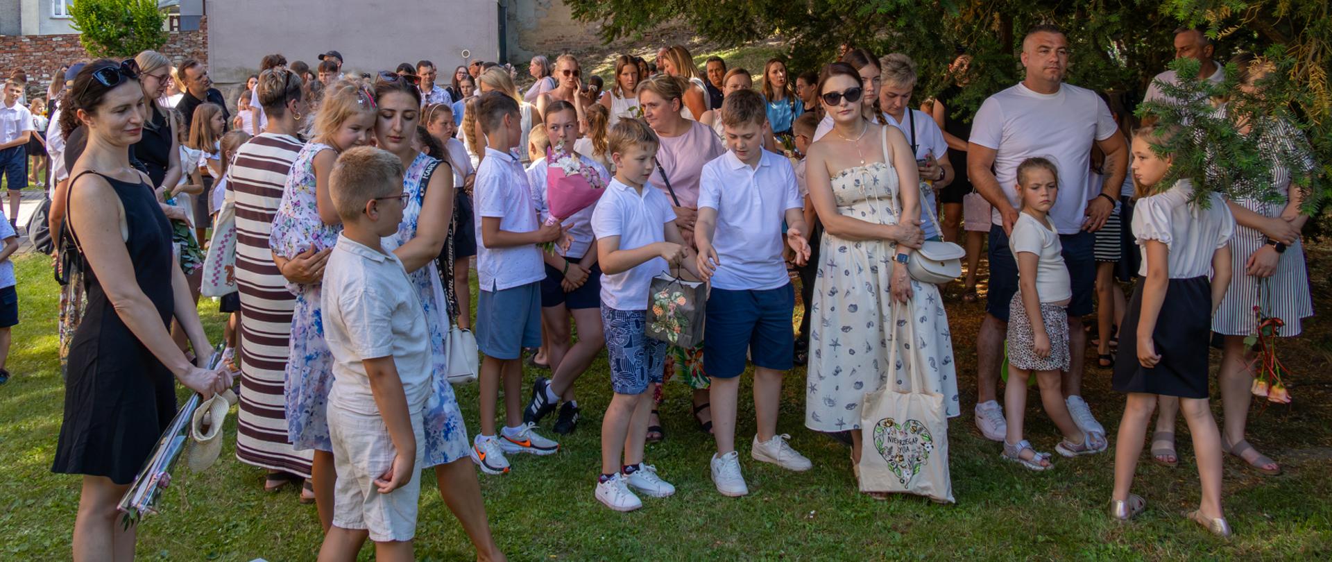 Rodzice i uczniowie zgromadzeni na szkolnym podwórku.