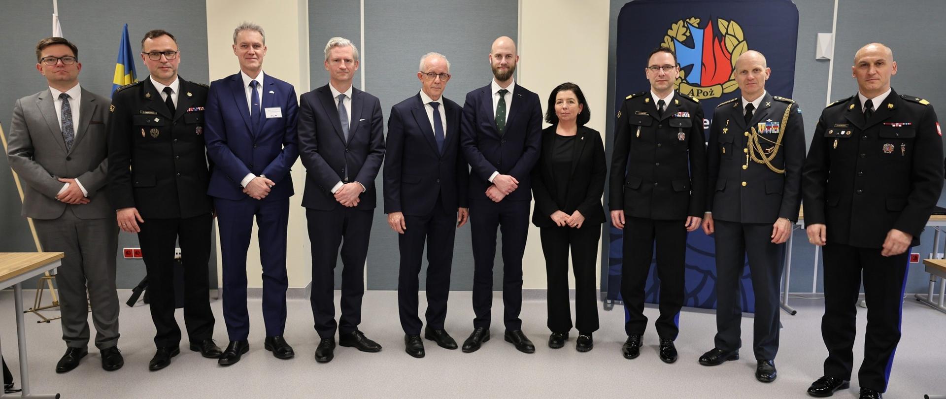 Uczestnicy delegacji oraz funkcjonariusze Państwowej Straży Pożarnej i przedstawiciele instytucji partnerskich pozują do wspólnego zdjęcia w Akademii Pożarniczej.