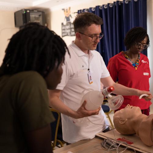 Instruktor demonstruje na manekinie zakładanie rurki ustno-gardłowej i prawidłowe umocowanie worka ambu do wentylacji tlenem