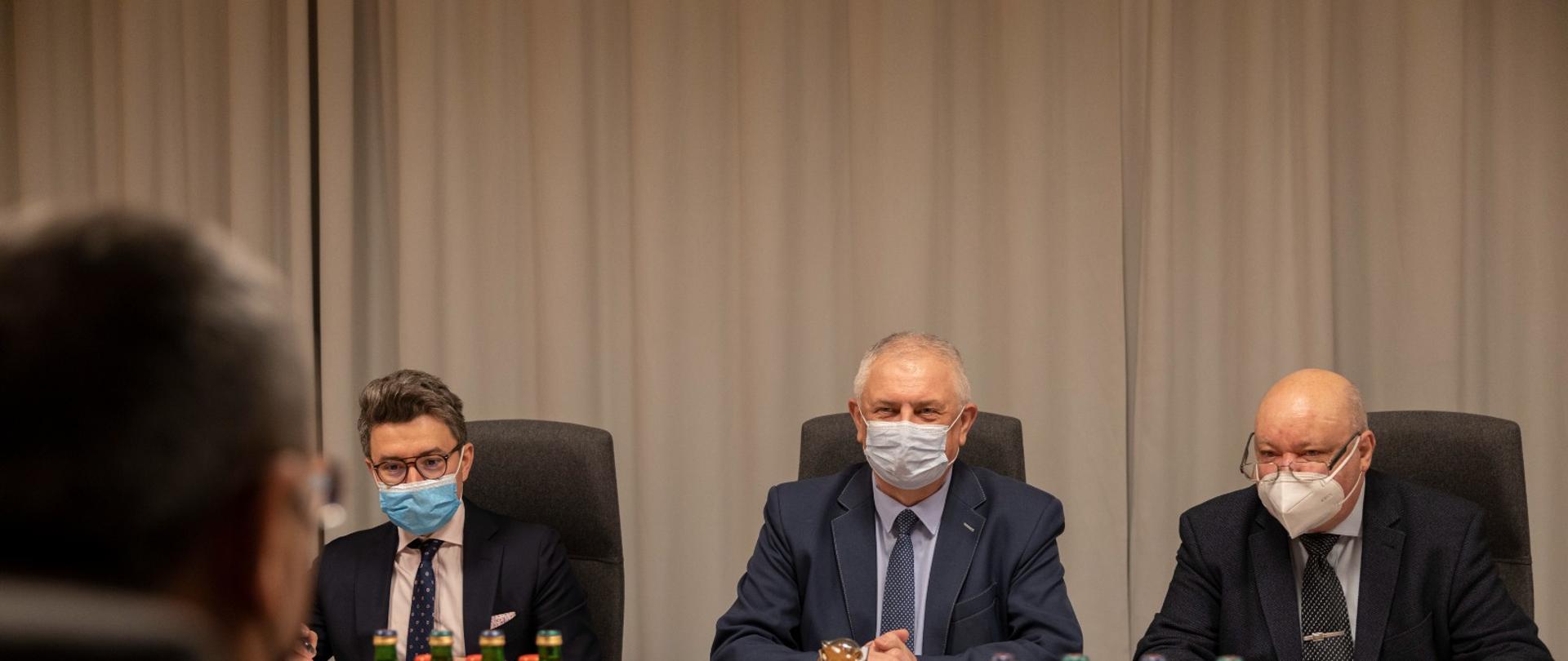 Deputy Minister Grzegorz Piechowiak during the meeting with Azerbaijan Ambassador. He sits behind a table with a mask on his face.