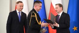 Na zdjęciu widać jak Prezydent RP oraz przewodniczący NSZZ Solidarność wręczają statuetkę i Certyfikat komendantowi powiatowemu PSP w Sandomierzu.