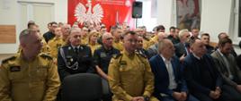 Strażacy siedzą w mundurach podczas odprawy rocznej średzkich strażaków