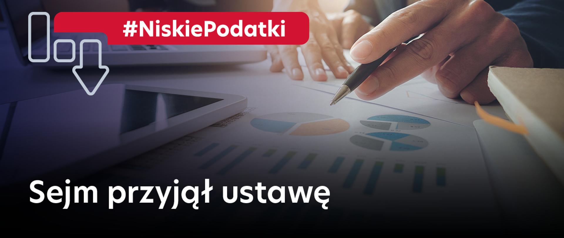 Napis Niskie Podatki Sejm przyjął ustawę plus wykresy słupkowe, długopis i dłonie