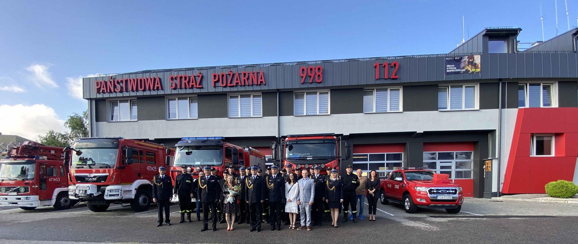 Zdjęcie zrobione w dzień. Na zdjęciu widać strażaków i samochody. 