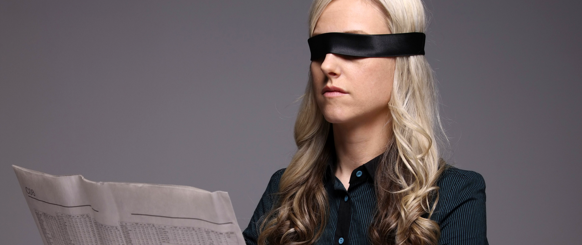 Kobieta z zawiązanymi oczami "czytająca" gazetę.