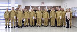 Grupowe zdjęcie funkcjonariuszy PSP (19 osób) w towarzystwie Zastępcy Komendanta Centralnej Szkoły PSP, kobiety oraz trzech funkcjonariuszy CS PSP