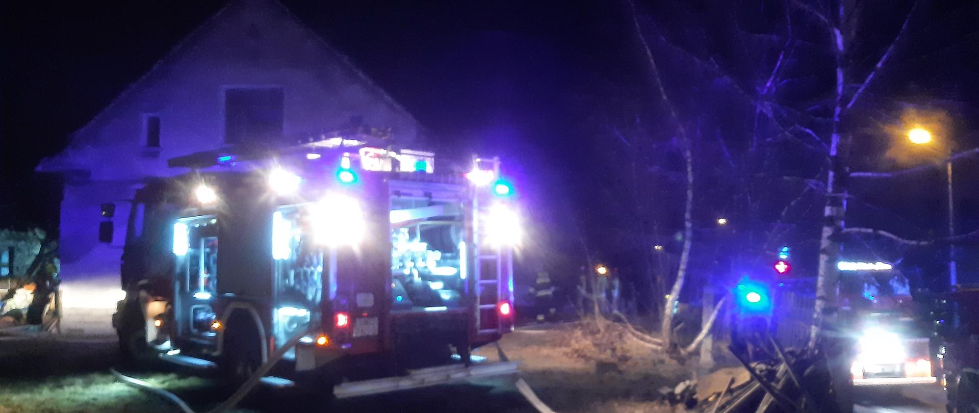 Na zdjęciu widać samochód gaśniczy na tle budynku w którym doszło do pożaru