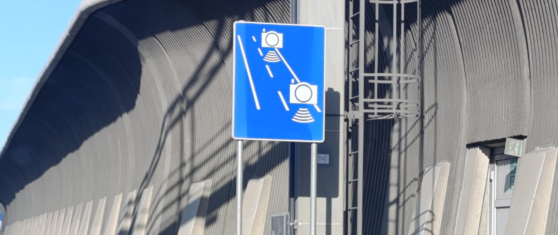 na zdjęciu widać znak drogowy informujący o odcinkowym pomiarze prędkości. w tle jadące samochody