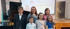 Zdjęcie przedstawiające wykonawców popisu klasy fortepianu pani Lilii Tarasenko, który odbył się 30 maja 2025 r. w auli szkoły.