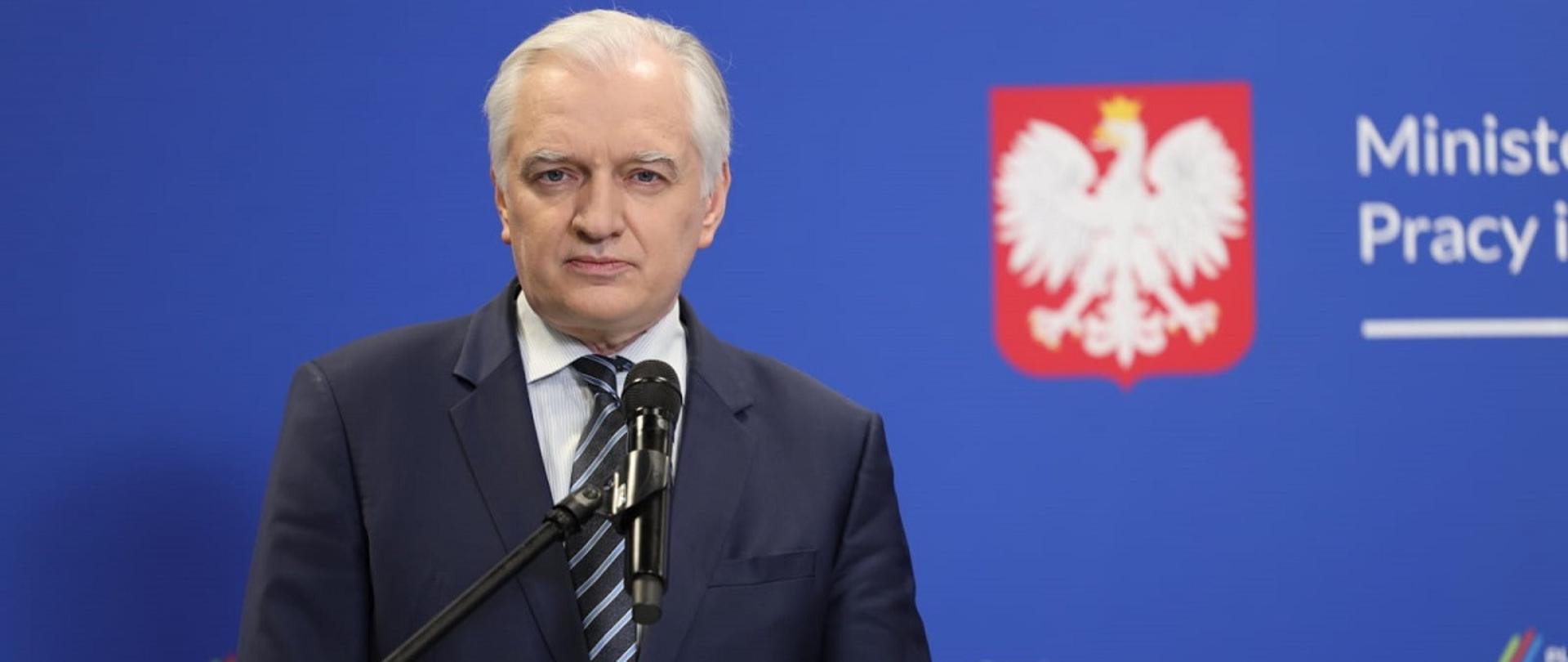 Wicepremier, minister rozwoju, pracy i technologii Jarosław Gowin, z tyłu za jego plecami baner MRPiT z godłem Polski i napisami "Plan dla Pracy i Rozwoju"
