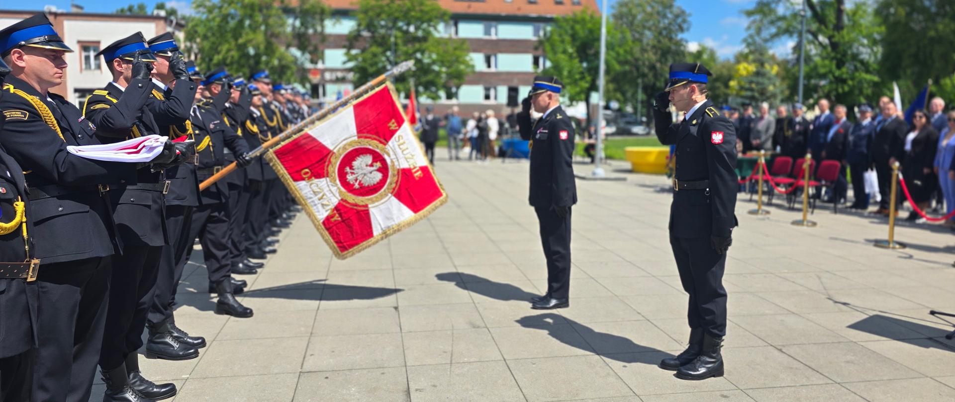 Komendant Wojewódzki i prowadzący uroczystość witają się ze sztandarem