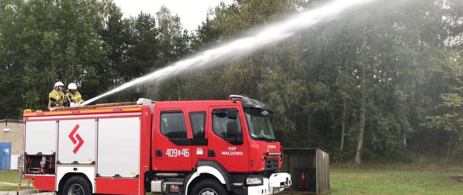 Na zdjęciu widać samochód pożarniczy podczas podawania wody z działka