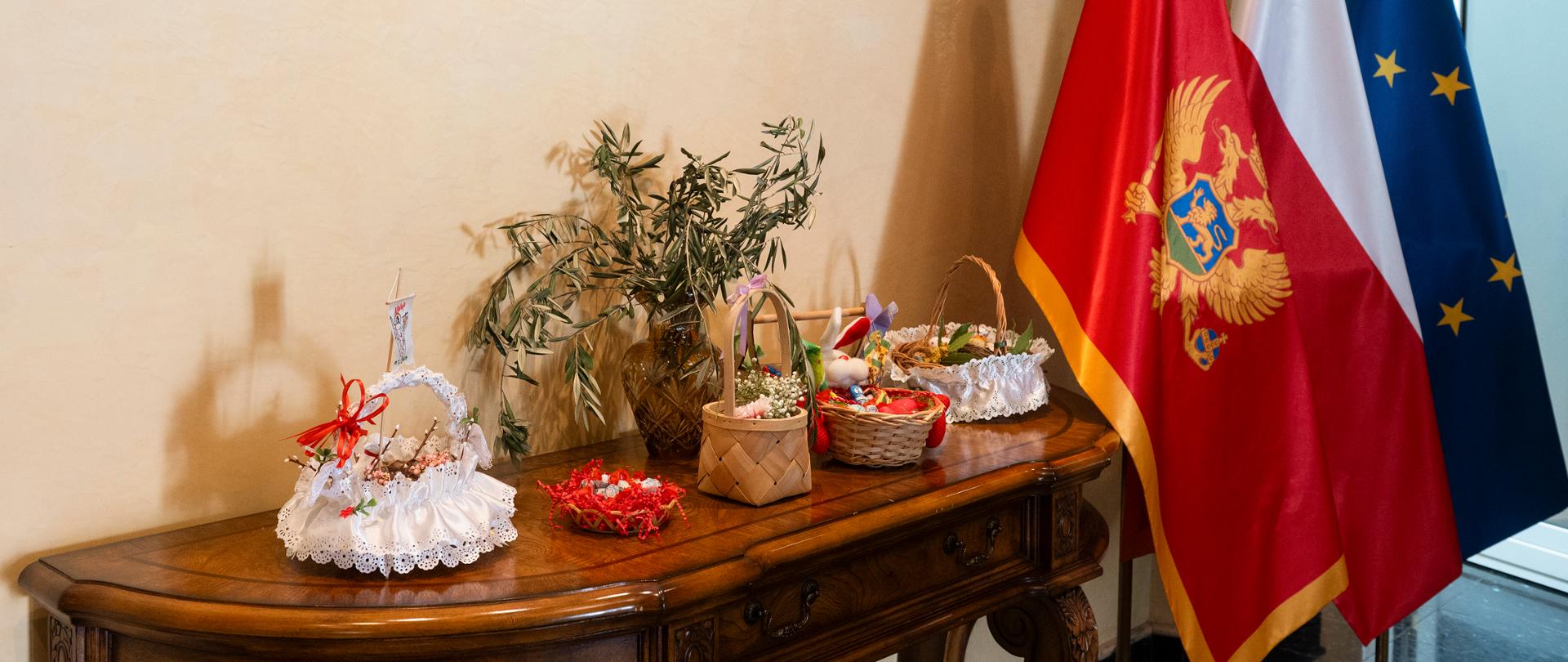 Uskršnje korpe na stolu pored zastava PL. CG. UE