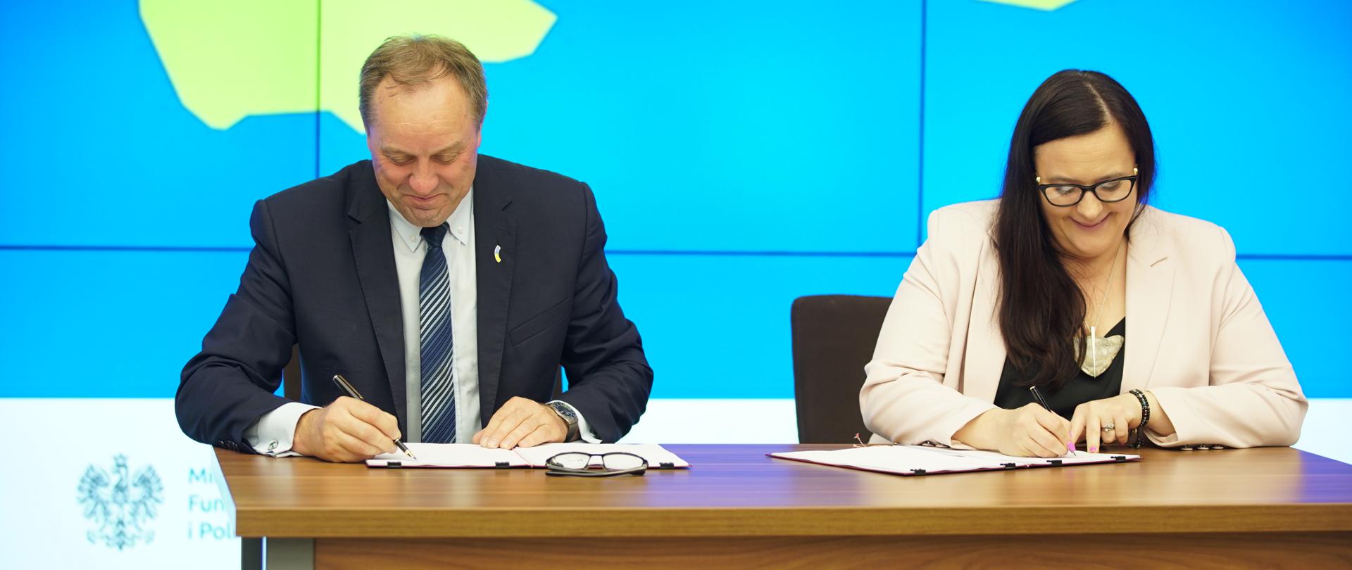 Wiceminister Małgorzata Jarosińska-Jedynak oraz marszałek Mieczysław Struk przy stole podpisują dokumenty
